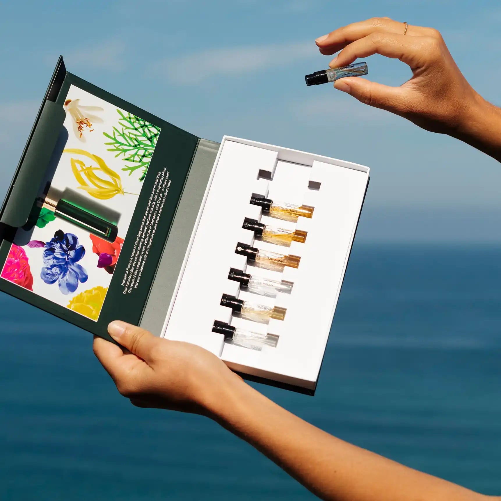 A set of small glass vials containing various shades of liquid, presented in a white and green open box.