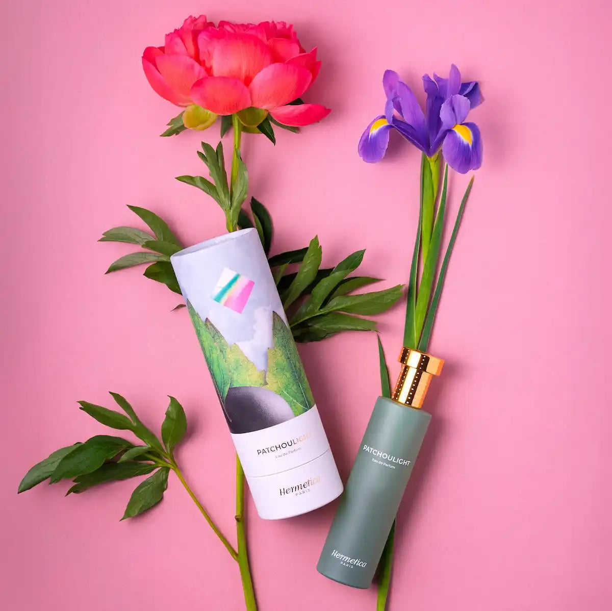 Two bottles of perfume, one in its box, with floral accents.