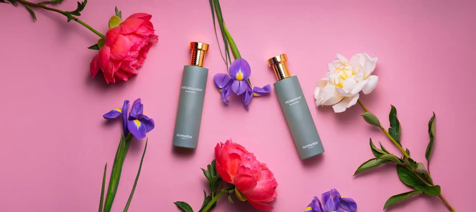 Two elegant gray spray bottles with gold caps, surrounded by colorful flowers.